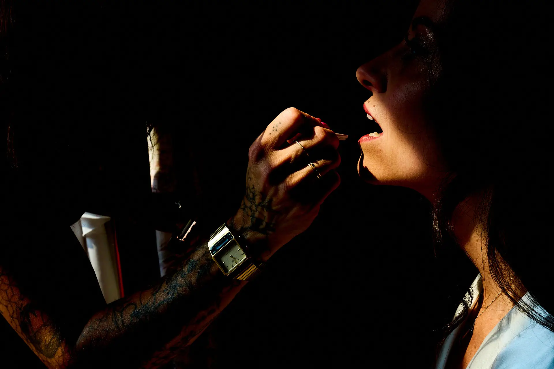 morning wedding preparations: artistic chiaroscuro photo of the bride's mouth during lip make-up