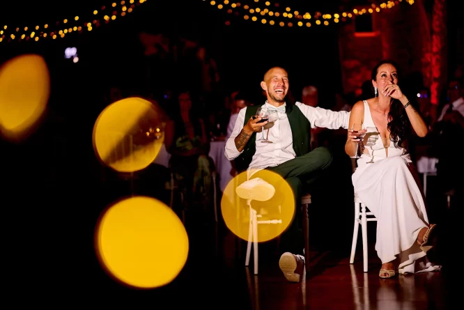 Cérémonie laïque au château de Miremont : la soirée avec diffusion d'une vidéo devant les mariés effets lumières du photographe de mariage bokeh jaune orange et guirlande lumineuse LED